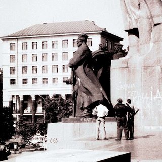Monument, soldiers, and building in a public square.