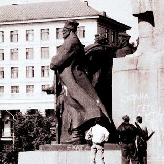 Monument, soldiers, and building in a public square.