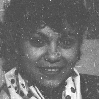 Black and white portrait of a smiling woman with a scarf.