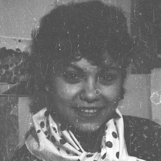 Black and white portrait of a smiling woman with a scarf.