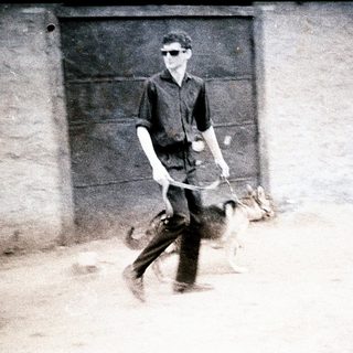 Man walks with dogs near a building.