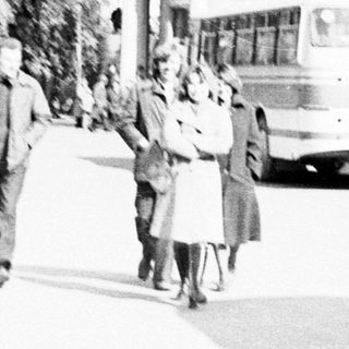 People walking near buses in a vintage, black and white scene.