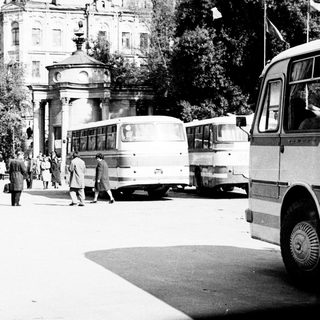 Black and white image of buses and people in a park.
