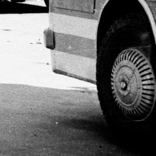 Black and white image of buses and people in a park.