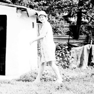 Two figures near a house with laundry hanging outside.