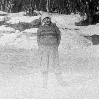 People in winter clothing stand in a snowy landscape.