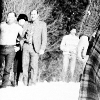 Woman stands in snowy landscape with a group behind her.