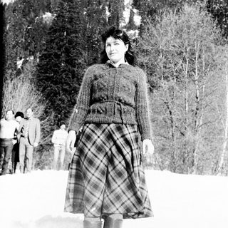 Woman stands in snowy landscape with a group behind her.