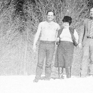 Group of people standing in snowy woods.