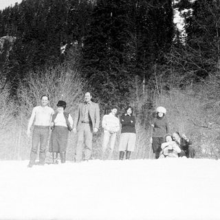 Group of people standing in snowy woods.