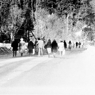 Group of people walking along a snowy road in mountains.