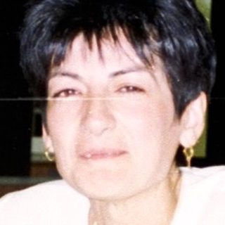 Woman sits at a table with drinks during a gathering.