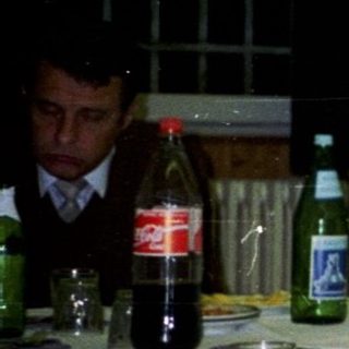 Woman sits at a table with drinks during a gathering.