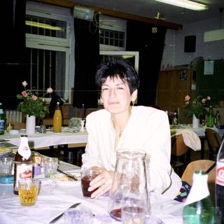 Woman sits at a table with drinks during a gathering.