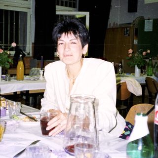 Woman sits at a table with drinks during a gathering.