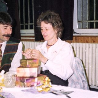 Three people seated at a table, gift exchange.