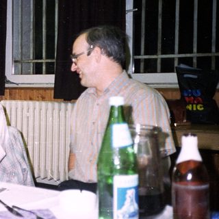 Three people seated at a table, gift exchange.