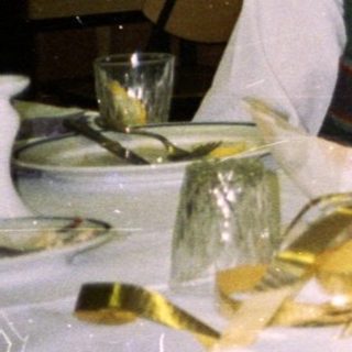 Three people seated at a table, gift exchange.
