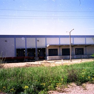 Industrial building with visible loading docks and surrounding vegetation.
