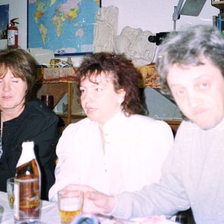 Three people seated at a table with decorations and books.