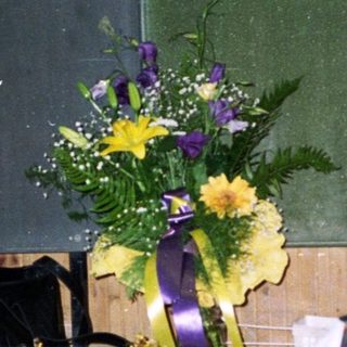 Two people sit with a floral arrangement nearby.
