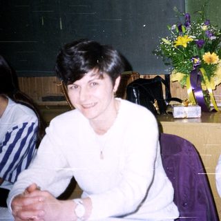 Two people sit with a floral arrangement nearby.