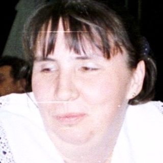 Woman sits at a table with tableware and floral display.