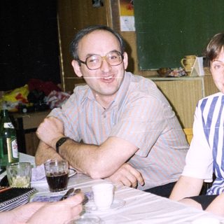 Three people sit at a table, appearing to be conversing.