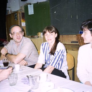 Three people sit at a table, appearing to be conversing.