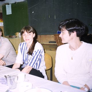 Three people sit at a table, appearing to be conversing.