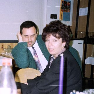 Three people sit at a table with food and drinks.
