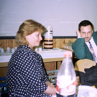 Three people sit at a table with food and drinks.