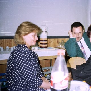 Three people sit at a table with food and drinks.