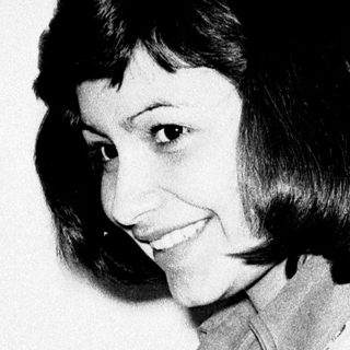 Woman holding a knife, smiling in a black and white photo.