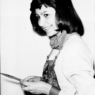 Woman holding a knife, smiling in a black and white photo.