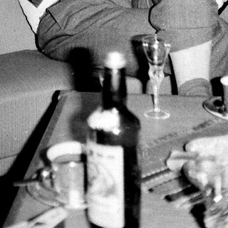 Man relaxes on a couch with drinks and artwork.