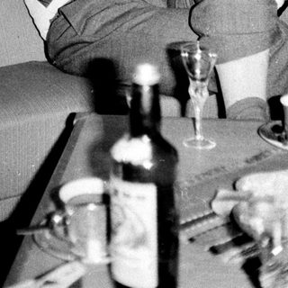 Man relaxes on a couch with drinks and artwork.