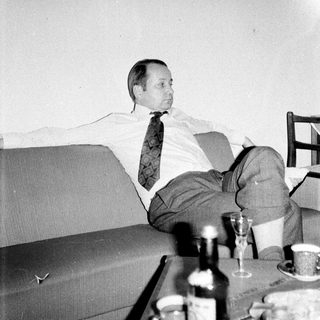 Man relaxes on a couch with drinks and artwork.