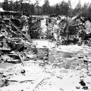 Snow-covered quarry with visible rock faces and machinery.