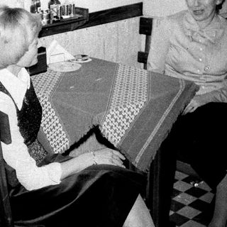 Two women seated at a table in a kitchen.