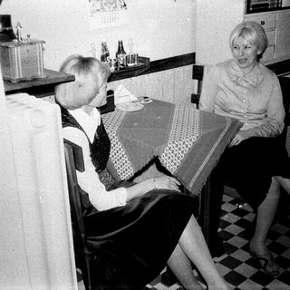 Two women seated at a table in a kitchen.