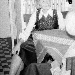 Here's a brief summary of the image: Woman seated in a kitchen, appearing distressed or unwell.