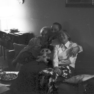 Couple relaxes on couch with child in a dimly lit room.