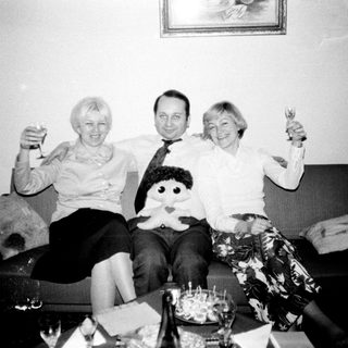 Couple and woman toasting on a sofa.