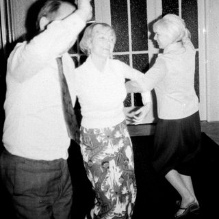 Three people dancing indoors, appearing to enjoy themselves.