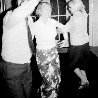 Three people dancing indoors, appearing to enjoy themselves.