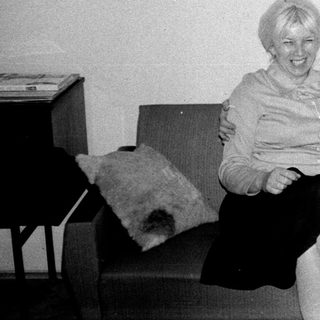 Here's a brief summary of the image: Three people sit on a couch; one holds a painting.