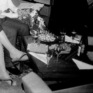 Here's a brief summary of the image: Three people seated on a sofa, in a vintage living room.