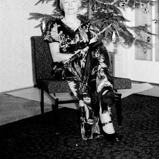 Woman seated with a small, decorated Christmas tree.
