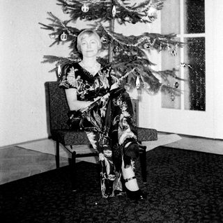 Woman seated with a small, decorated Christmas tree.
